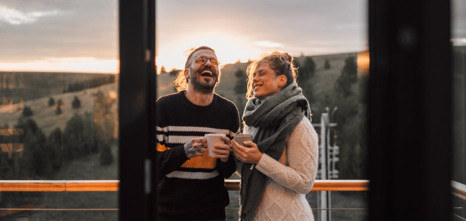 Ein Mann und eine Frau die eine Kaffeetasse halten und lachen