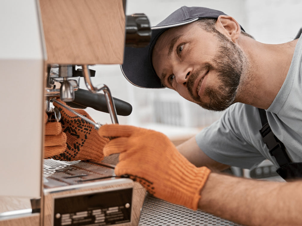 Eine Kaffeemaschine wird von einem Mann repariert 